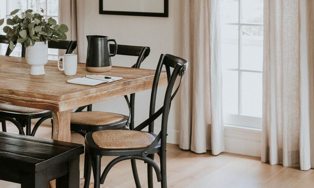 A wooden table on the left and dark-brown framed chairs around
