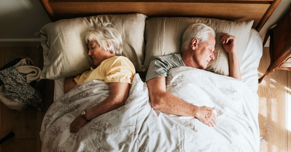 Two young ladies talking one holding a book another with box in a collge dorm
