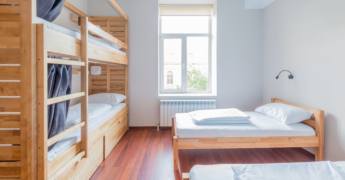 A wooden bunker bed and a bed in a collge dorm. White and natural wood combination