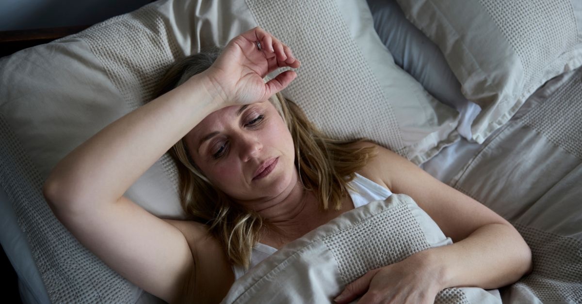 Two young ladies talking one holding a book another with box in a collge dorm