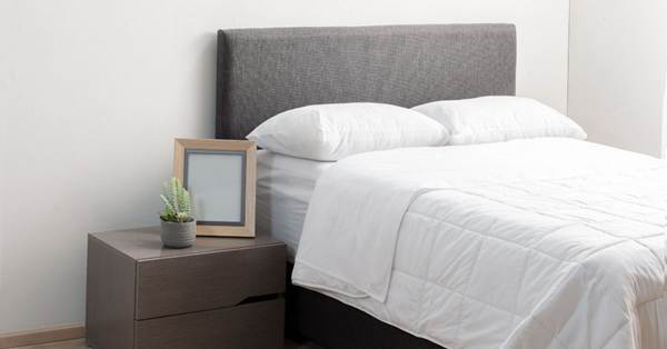 A man hold mattress vertically to move.