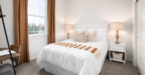 Bedroom in which there is a bed and night stand lamps on both side.